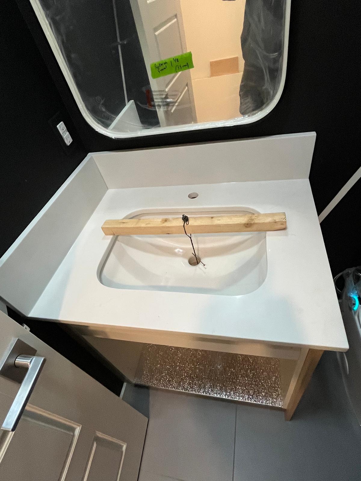 Dark cabinet bathroom vanity with white quartz top and integrated rectangular sink