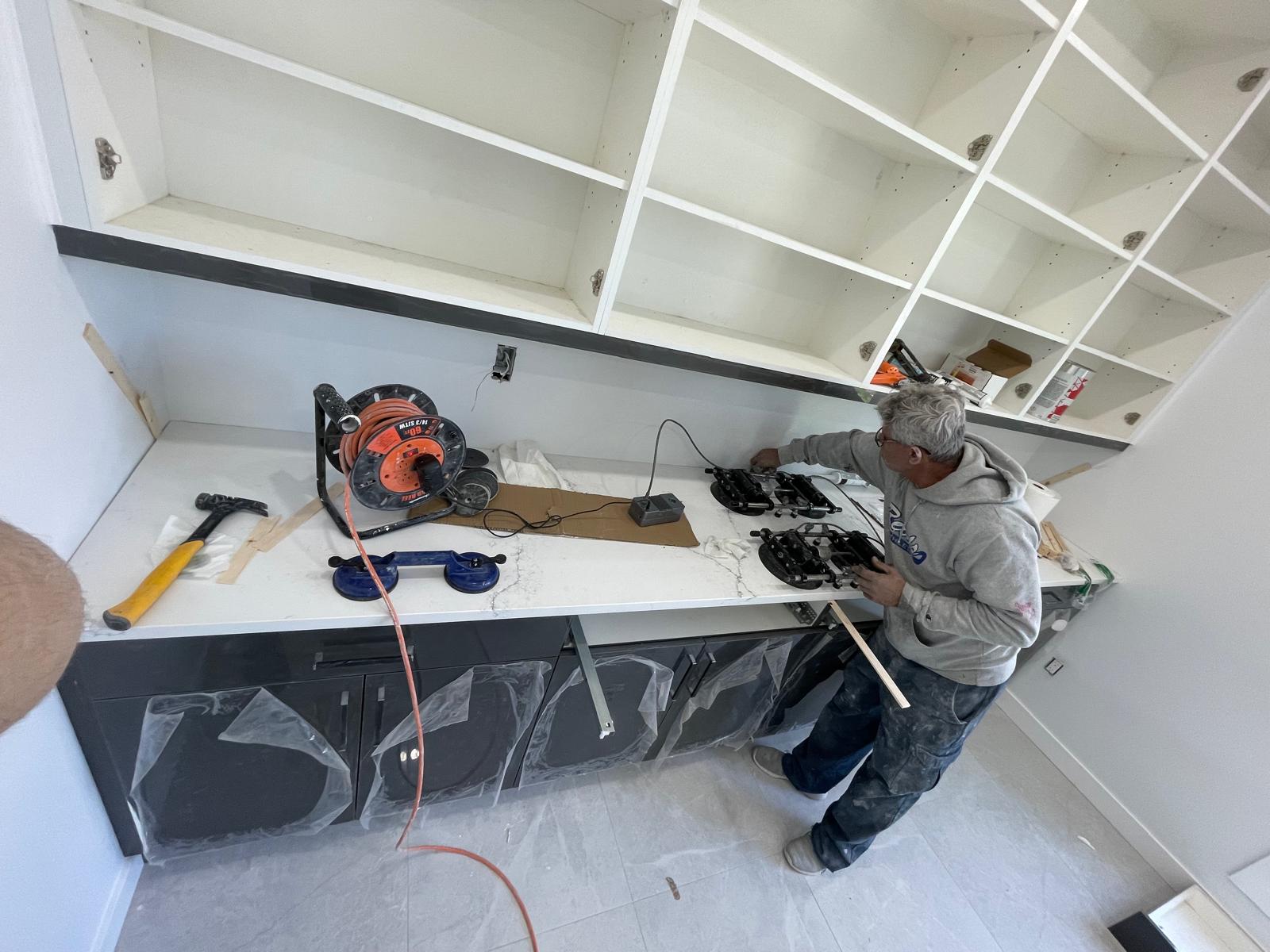 Installer fitting marble countertop on built-in unit with shelving