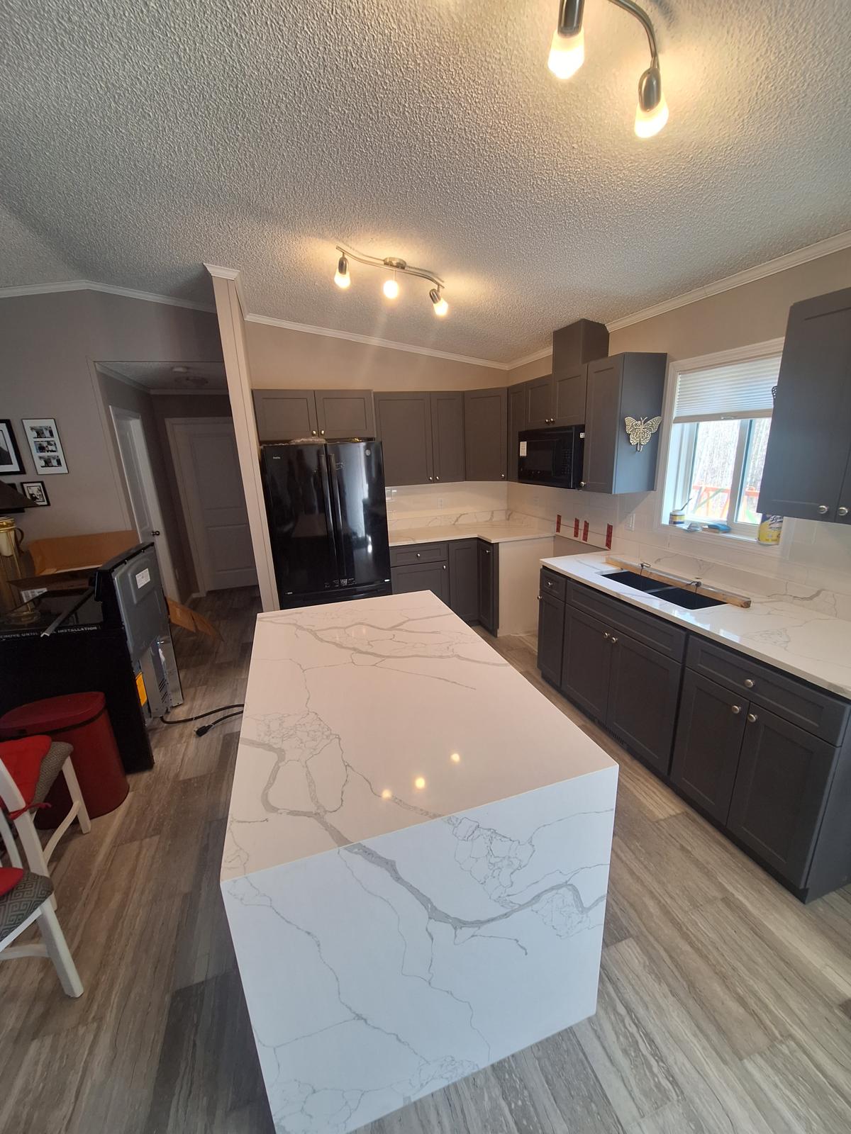 Dark grey kitchen with marble-look quartz waterfall island