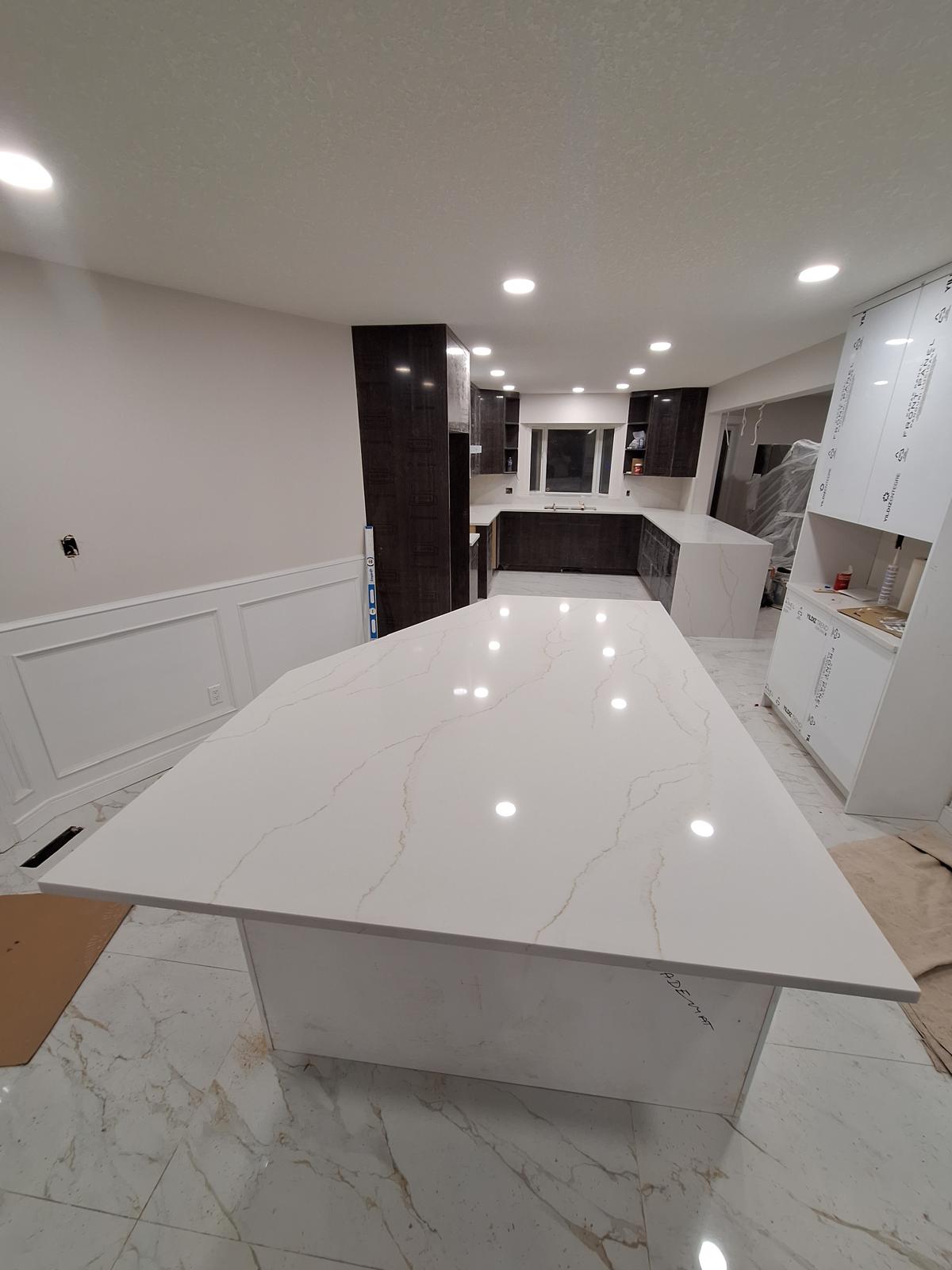 Modern kitchen with large white quartz island under construction